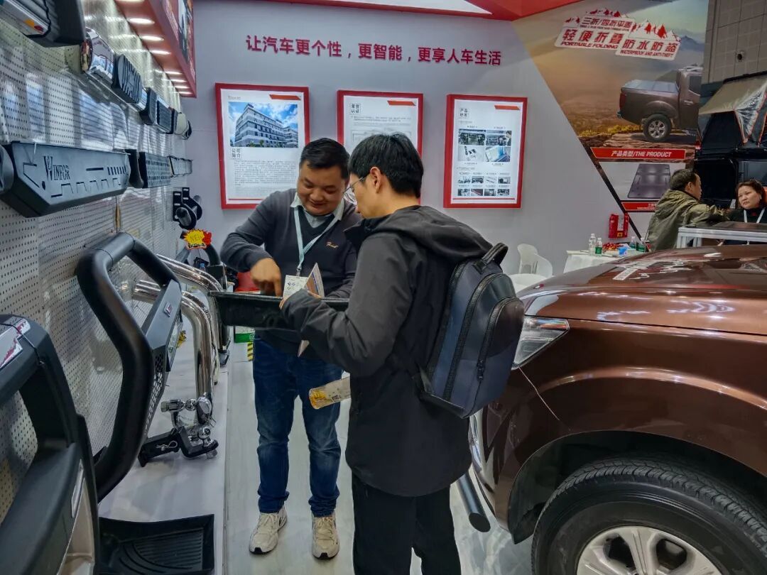 Buyer examining a pickup tonneau cover sample at the WINFOR stand, discussing an OEM and ODM customisation
