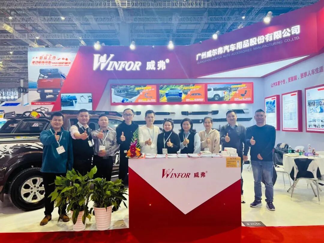 WINFOR team group photo with customers in front of the stand at Automechanika Shanghai 2023, with the product wall and a display vehicle behind them