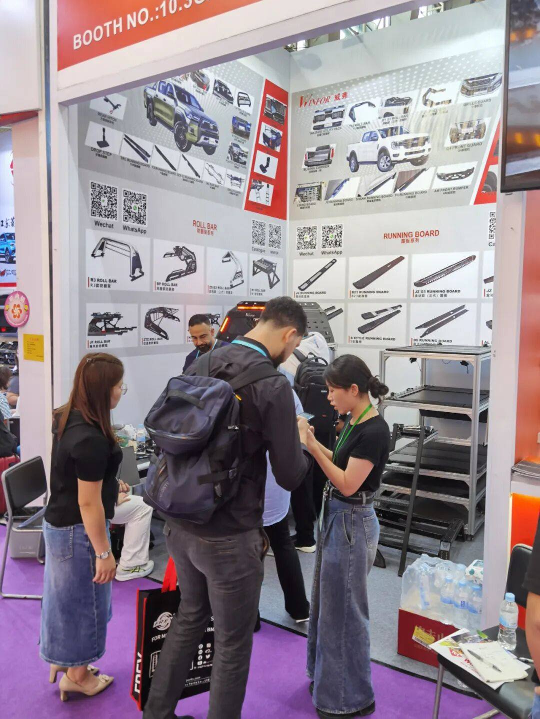 Buyer examining a pickup tonneau cover sample at the WINFOR Canton Fair booth while a staff member explains the product details