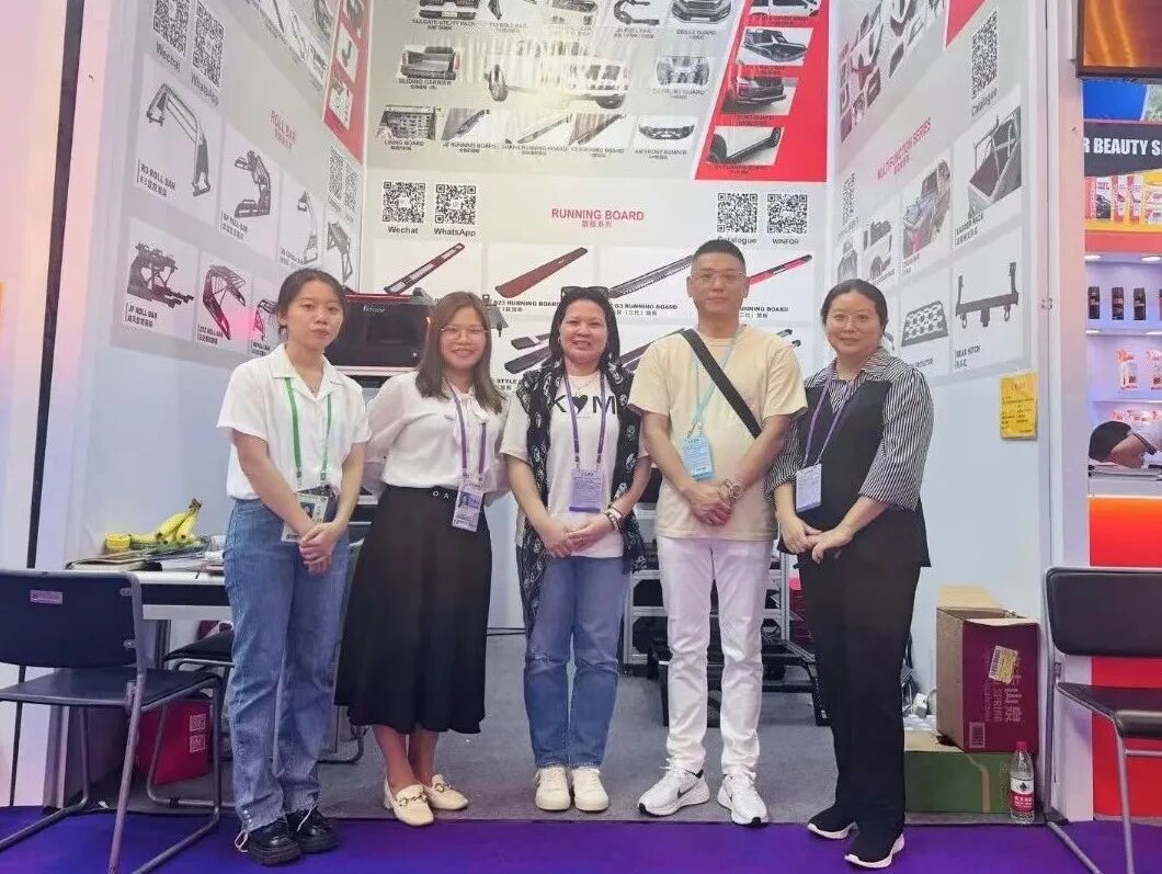 WINFOR booth team posing with an overseas customer at the 136th Canton Fair in 2024, in front of the pickup bed cover display wall
