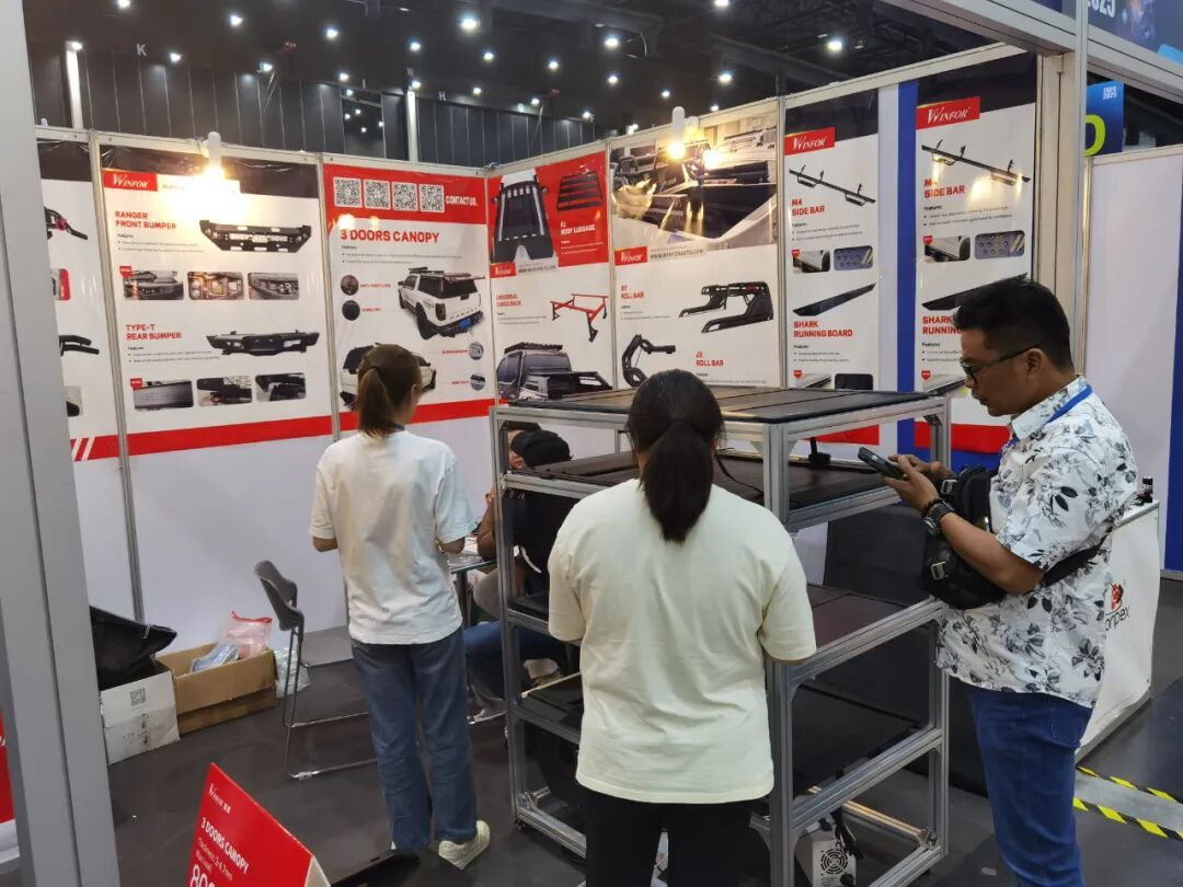 Buyer talking with a WINFOR representative at the stand during TAPA 2025 in Bangkok, with the pickup bed cover display behind