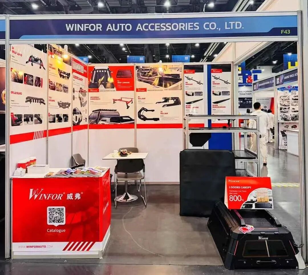 Overview of the WINFOR stand at TAPA 2025 in Bangkok, booth EH1018F43, showing the pickup bed cover display wall and samples on the counter